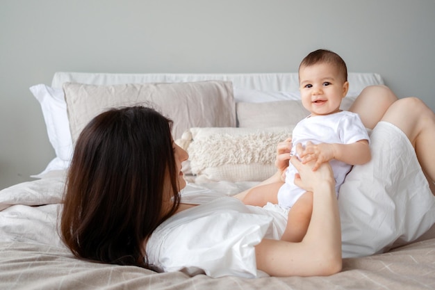 Een jonge moeder speelt met haar kleine kind zittend op het bed