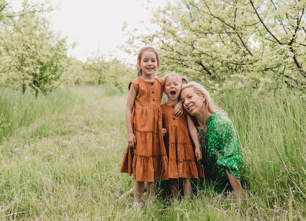 Een jonge moeder speelt met twee jonge dochters in de lentetuin. blije kinderen en mama