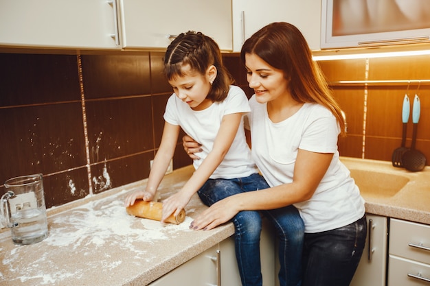 een jonge moeder staat in de keuken en werkt samen met haar kind met meel