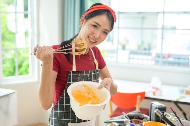 Een jonge, mooie Aziatische vrouw bakt in haar keuken-, bakkerij- en koffiewinkelbedrijf