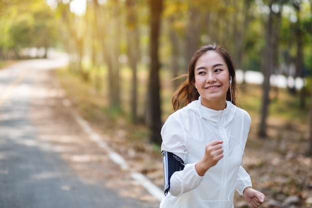 Een jonge, mooie aziatische vrouw die 's ochtends in het stadspark jogt