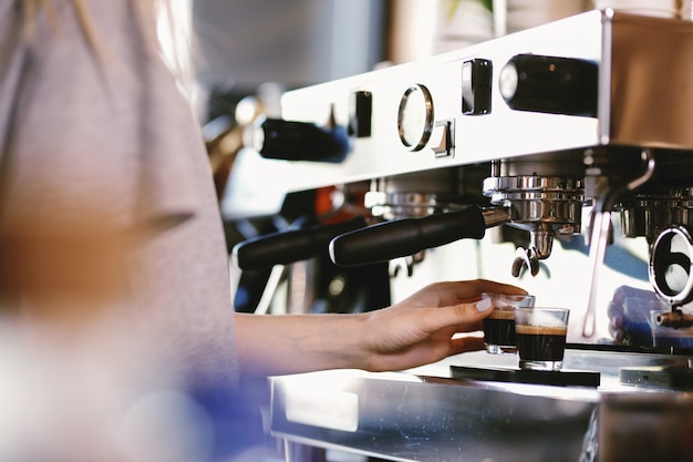 Een jonge mooie blonde, casual outfit draagt, neemt een kopje verse koffie uit een dure koffiemachine in een moderne coffeeshop. .