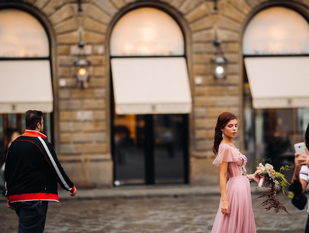 Een jonge mooie bruid staat in het centrum van de oude stad Florence in Italië. Bruid in een mooie roze jurk met een boeket in Toscane.Italië.