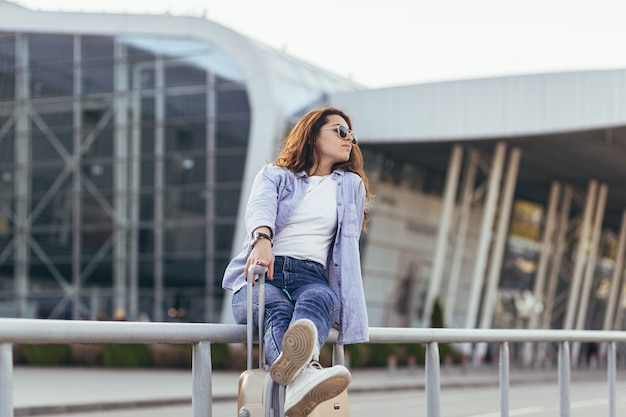 Een jonge mooie studente verlaat de luchthaven in een nieuwe stad en wacht op een taxi