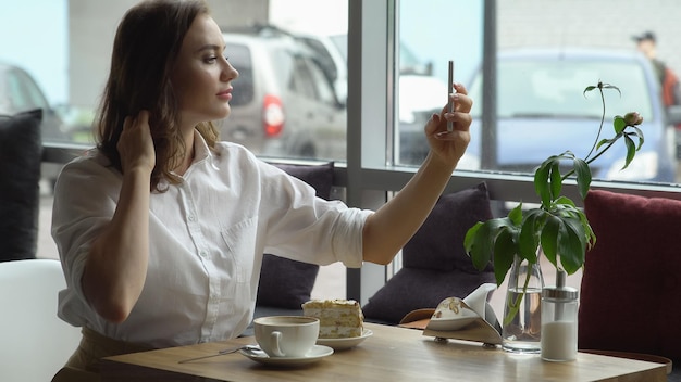 Een jonge mooie vrouw die koffie drinkt in een café. jonge vrouw in zakelijke kleding op een lunchpauze.