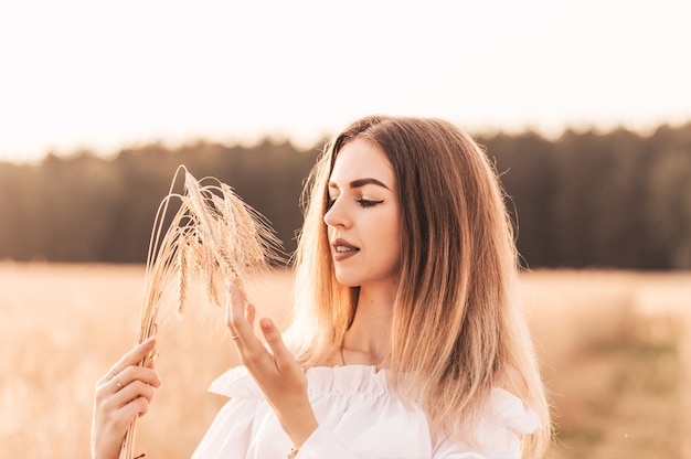 Een jonge mooie vrouw loopt door een tarweveld in witte kleren