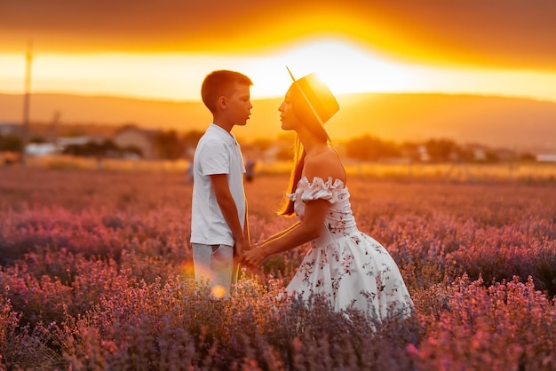 Een jonge mooie vrouw loopt met haar zoon door een prachtig lavendelveld en geniet van de geur van bloemen Rust en prachtige natuur Lavendel bloeiend en bloemen plukken