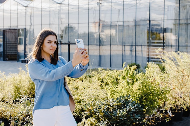 Een jonge mooie vrouw staat in de buurt van een bloemencentrum en praat tijdens een videogesprek aan de telefoon Een vrouw neemt foto's van de straat en neemt een selfie