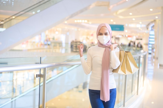 Een jonge moslimvrouw die een beschermend masker draagt in een winkelcentrum