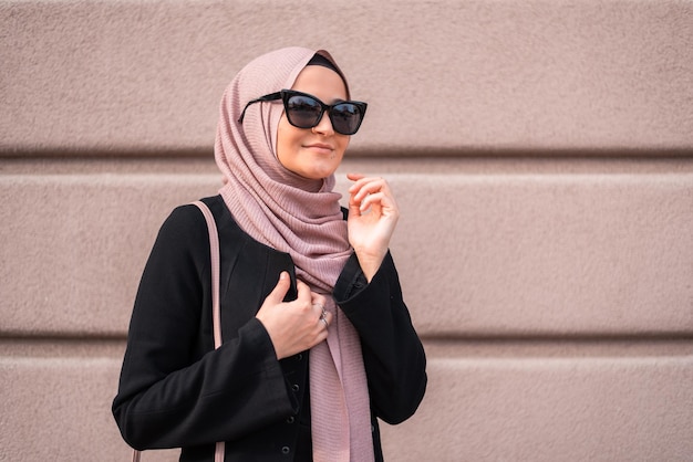 Een jonge moslimvrouw in modieuze hijab geïsoleerd op de achtergrond