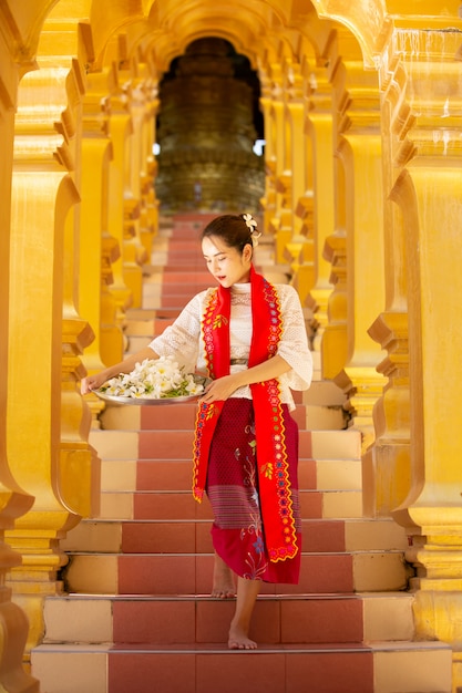 Een jonge Myanmar-vrouw in een traditioneel welkomstgebaar met Shwedagon-pagode