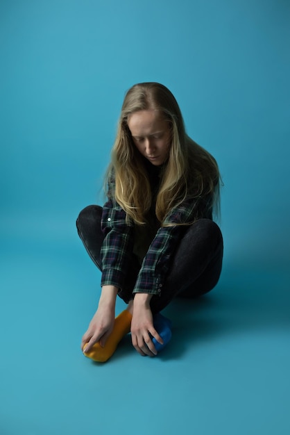 Een jonge Oekraïense vrouw op een geïsoleerde blauwe achtergrond in de studio Moderne blonde in gele blauwe sokken tijdens de oorlog in Oekraïne voor de ondersteuning van de vrede