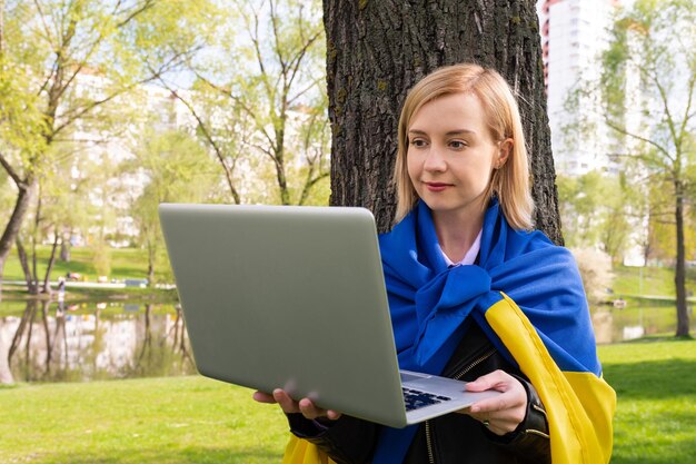 Een jonge Oekraïense vrouw werkt op een laptop in het park Business onderwijs afgelegen levensstijl