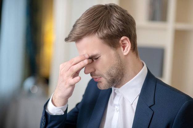 Een jonge officieel geklede man met hoofdpijn