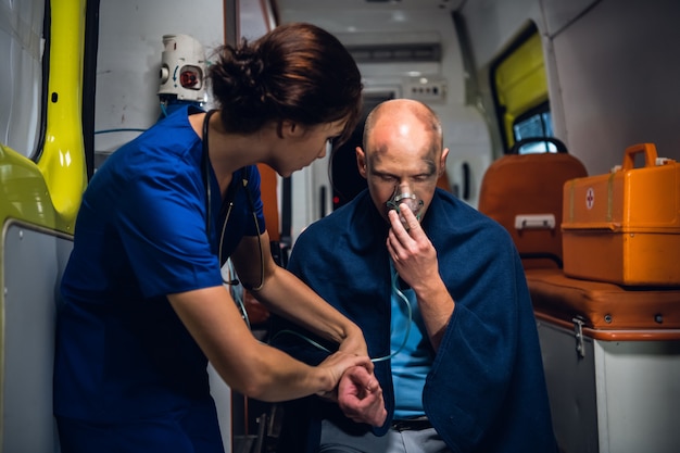 Een jonge paramedicus die met een gewonde man praat en hem probeert te kalmeren