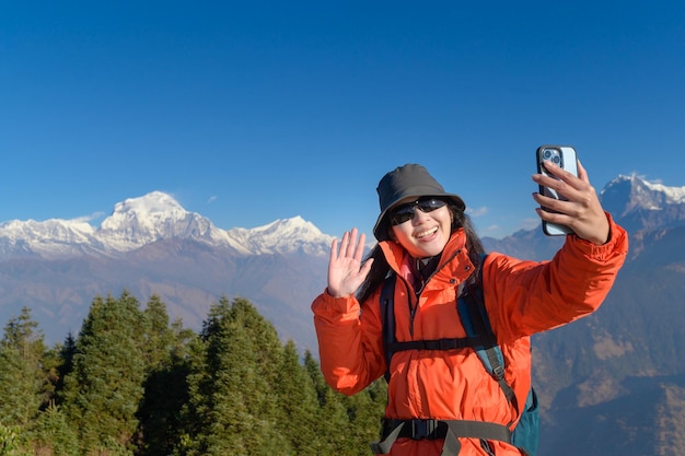 Een jonge reiziger maakt een selfie of een videogesprek terwijl hij op de top van een berg staat