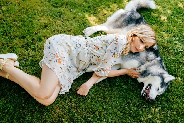 Een jonge romantische vrouw die met een gelukkige hond op het gras ligt