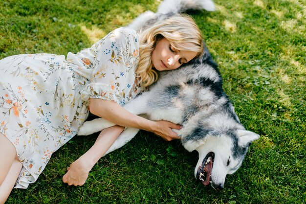 Een jonge romantische vrouw die met een hond op het gras ligt