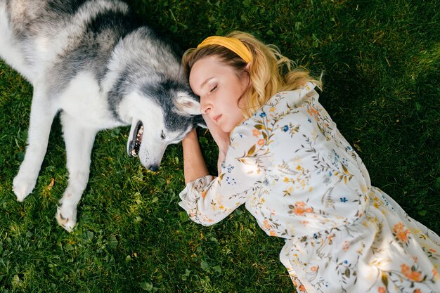 Een jonge romantische vrouw die met een hond op het gras ligt