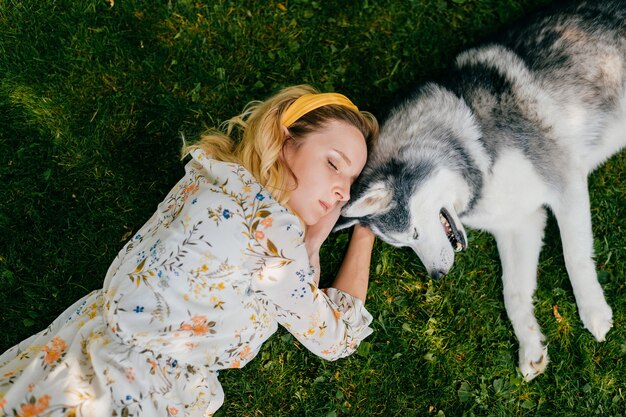 Een jonge romantische vrouw die met een hond op het gras ligt