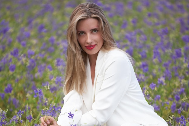 Foto een jonge slanke vrouw in een witte jurk loopt in de zomer in een bloemenveld