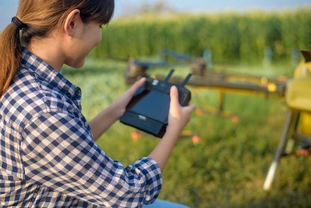 Een jonge slimme boer die een drone bestuurt die kunstmest en pesticiden over landbouwgrond sproeit