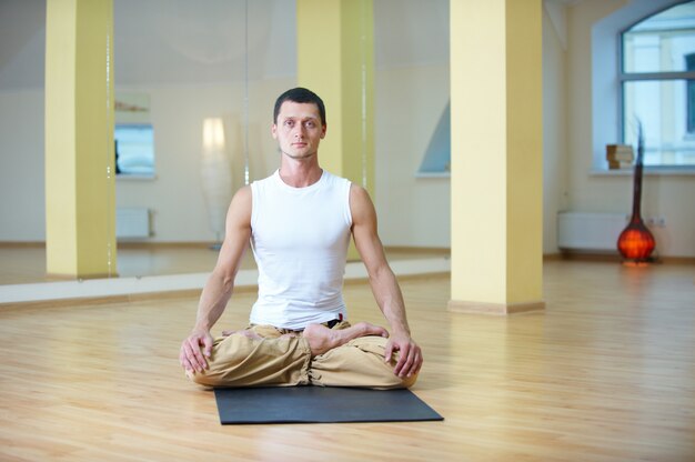 Een jonge sterke man die yoga-oefeningen doet. lotus pose en mediteert met padmasana benen in de yogastudio