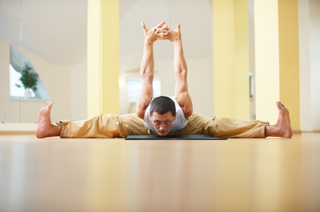Een jonge sterke man die yoga-oefeningen doet - Samakonasana rechte hoek pose in de yogastudio