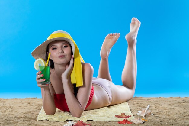 Een jonge tiener ligt op het strand met een alcoholische drank en zonnebaden in de zomerzon