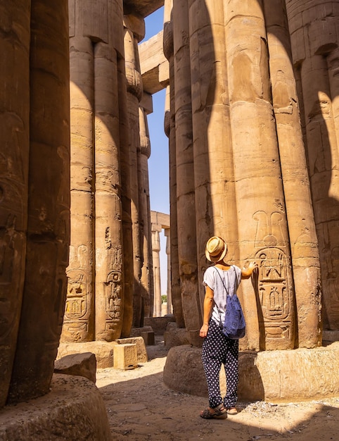 Een jonge toerist in een witte t-shirt en hoed die naar de oude Egyptische tempel van Luxor, Egypte kijkt