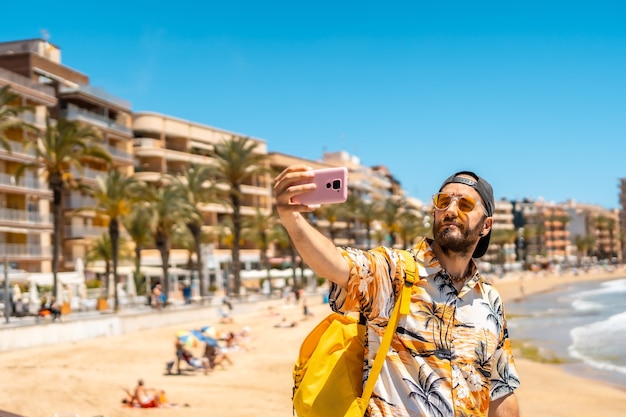 Een jonge toerist met de telefoon op playa del cura in de kustplaats torrevieja, alicante, valenciaanse gemeenschap