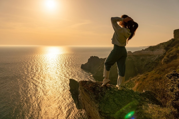 Een jonge toerist Vrouw geniet van zonsondergang boven het berglandschap van de zee terwijl ze buiten zit Yoga-fitnessroutine voor vrouwen Gezonde levensstijl, harmonie en meditatie