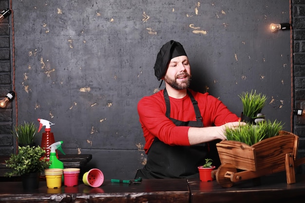 Een jonge tuinman zorgt voor zaailingen en snijdt bloemenTuinman met een bloembak Man die zorgt voor het planten van zaailingen in het voorjaar