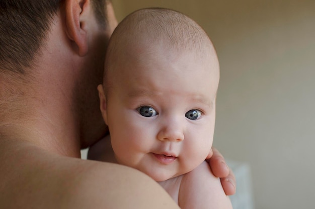 Een jonge vader houdt een pasgeboren baby vast Close-up gezicht portret vader en dochter familie thuis