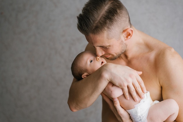 Een jonge vader houdt zijn pasgeboren zoon in een luier in zijn armen