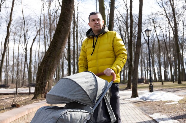 Een jonge vader loopt met zijn zoon in het park met een kinderwagen