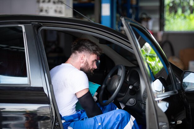 Een jonge voertuigtechnicus die in een auto werkt in een auto-reparatiewerkplaats