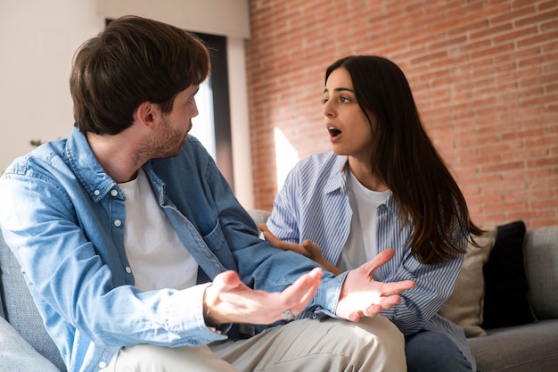 Een jonge volwassen man die slecht praat met zijn vriendin over jaloezie en bedrog in een relatie Problemen in het huwelijk met een verontwaardigde man Vrouw die hem uitlegt dat hij niet schuldig is en bedriegerMensen verontwaardigd