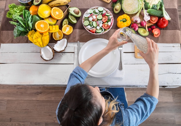 Een jonge vrouw aan de eettafel giet water in