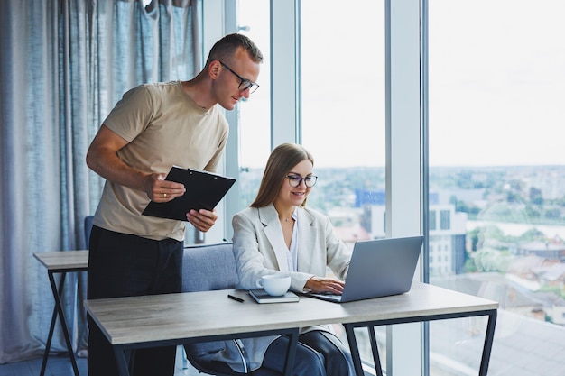 Een jonge vrouw aan een laptop met een bril zit aan een tafel met een zakelijke zakelijke bijeenkomst met collega's in een modern kantoor zakelijke carrièreconcept Vrije ruimte selectieve focus