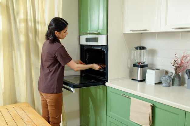 Een jonge vrouw bakt in een oven die ergonomisch op borsthoogte is ingebouwd