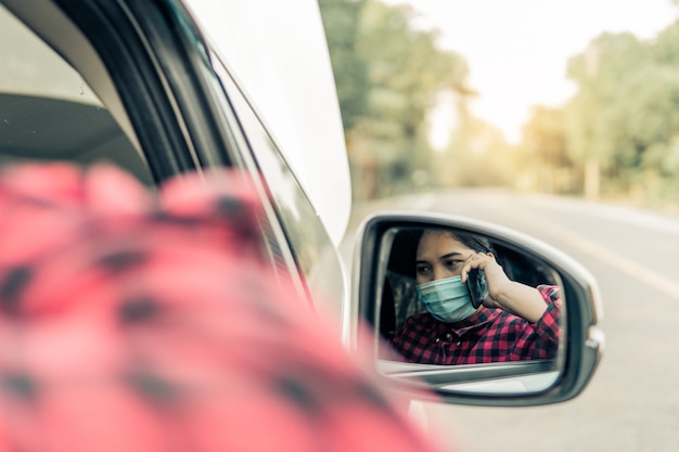 Een jonge vrouw belt een verzekering terwijl de auto kapot is.