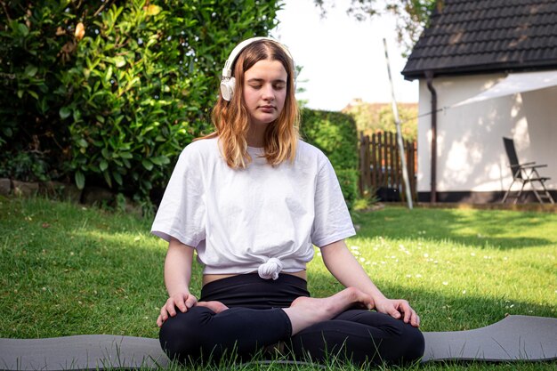 Een jonge vrouw beoefent yoga in de natuur op het gras in de tuin