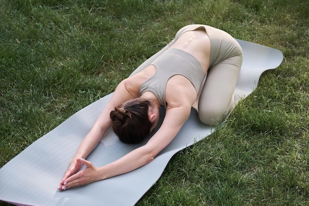 Een jonge vrouw beoefent yoga terwijl ze op een gymmat ligt