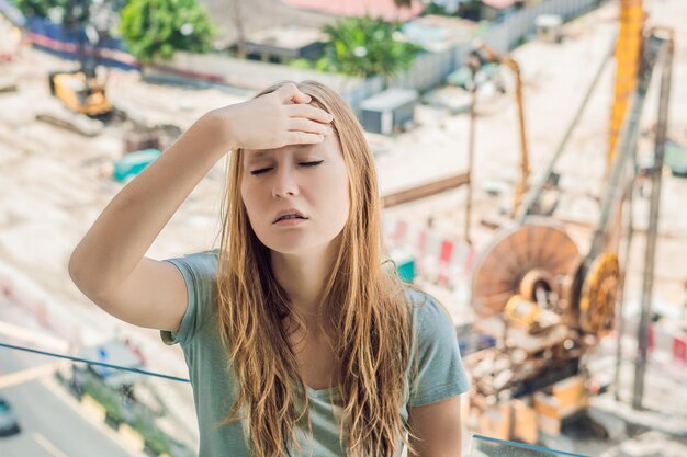 Een jonge vrouw bij het raam, geïrriteerd door het gebouw, werkt buiten. Geluidsconcept