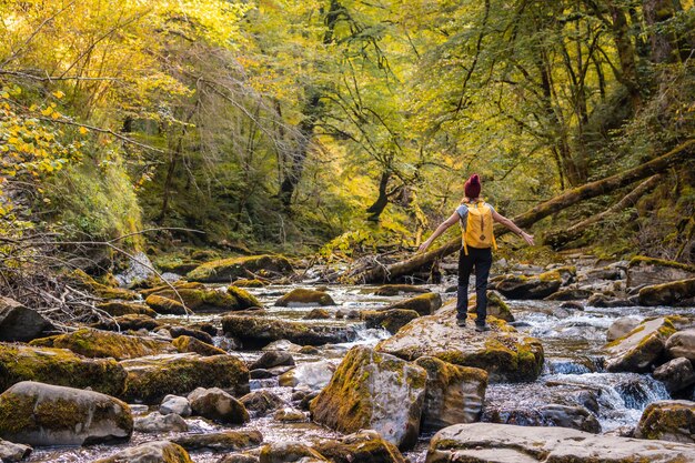 Een jonge vrouw bij zonsondergang op de rivier op het pad naar de holtzarte-hangbrug, larrau. in het bos of de jungle van irati, pyrénées-atlantiques van frankrijk