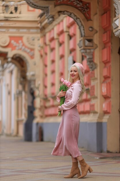 Een jonge vrouw buiten met een boeket roze tulpen geniet van de geur van haar favoriete bloemen Een geschenk van een man voor zijn vrouw en moeder Vakantie Internationale Vrouwendag 8 maart