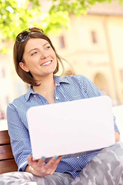 een jonge vrouw die aan laptop in het park werkt