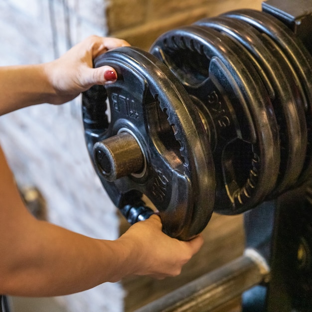 Een jonge vrouw die barbell voorbereidt voor het trainen van dichtbij