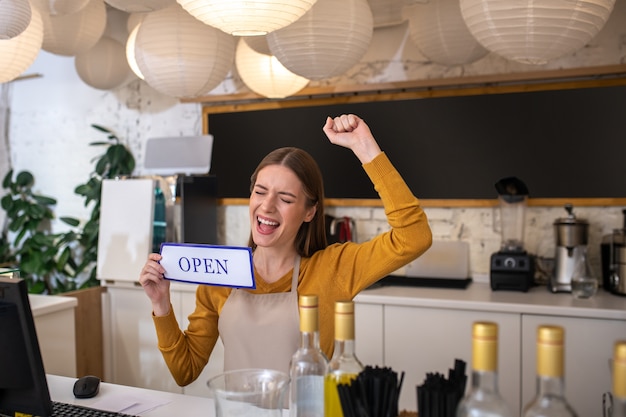 Een jonge vrouw die blij was met het openen van haar koffiehuis